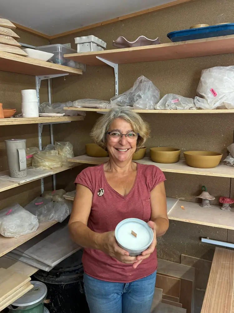 Aline, d'AZ poterie, souriante dans son atelier, tient une bougie coulée dans un bol en céramique